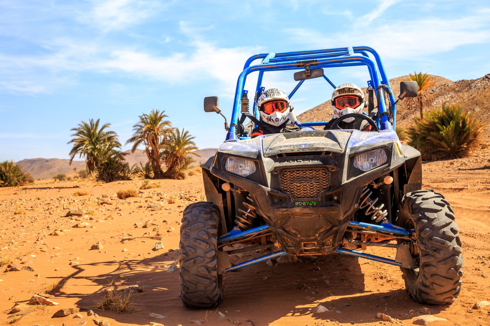 Blue offroad vehicle with two passengers in the desert